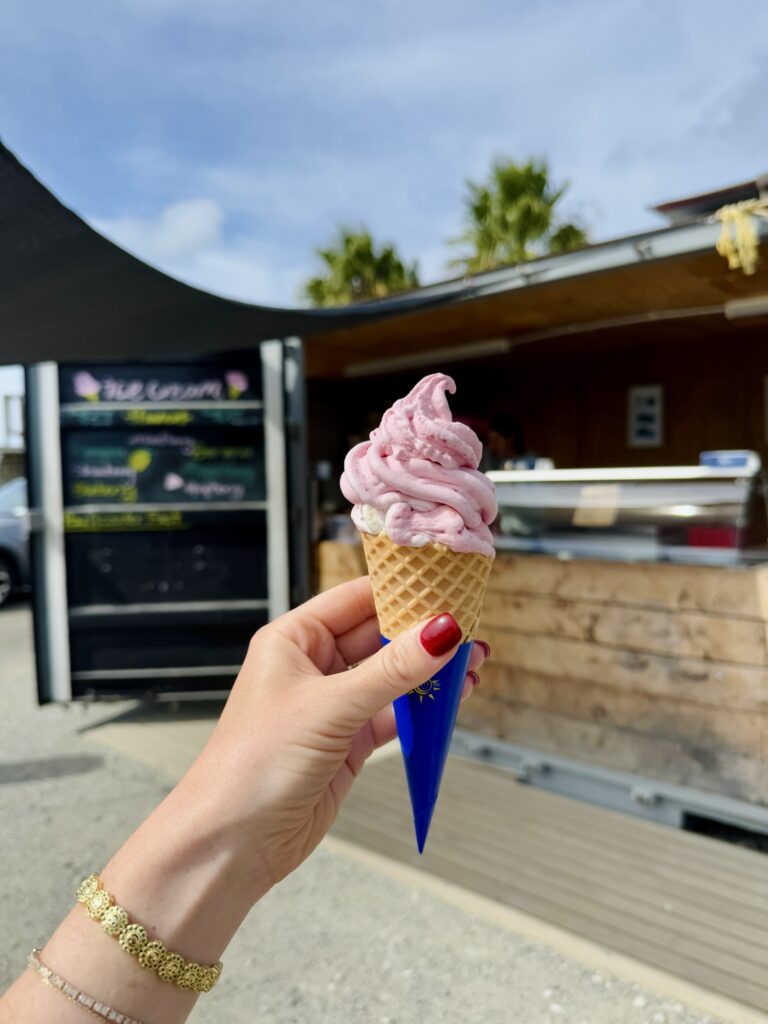 pink ice cream held up by a girl with red fingernails