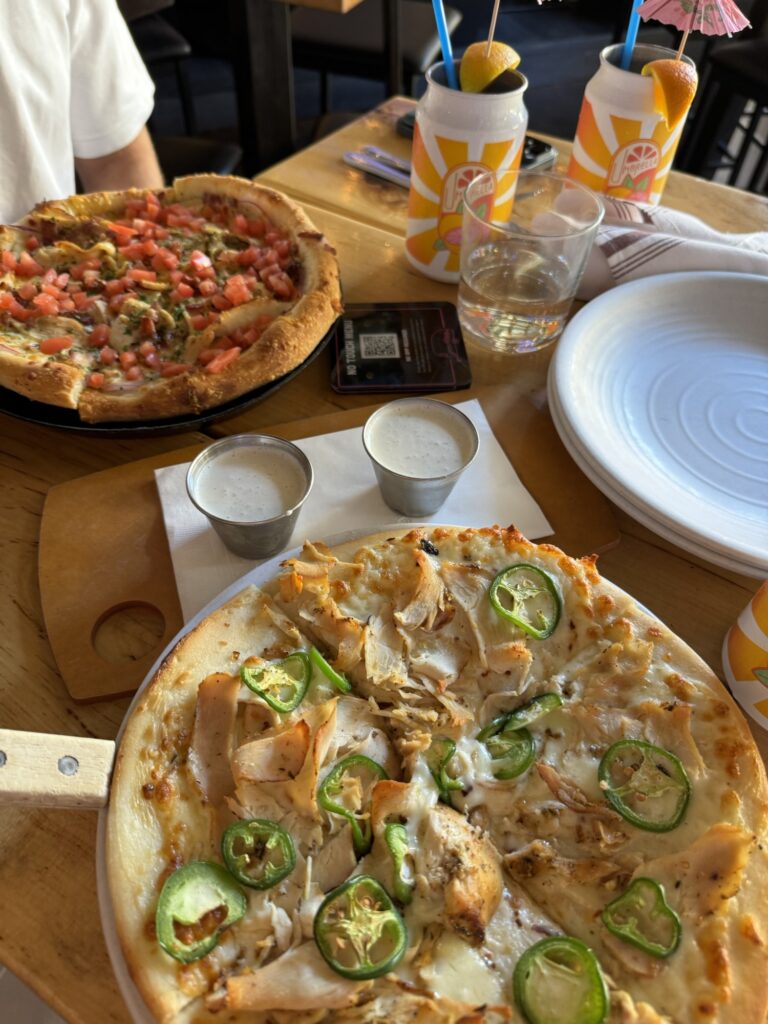 two pizzas, one with jalapenos and chicken, the other with sausage from happy camper in Chicago